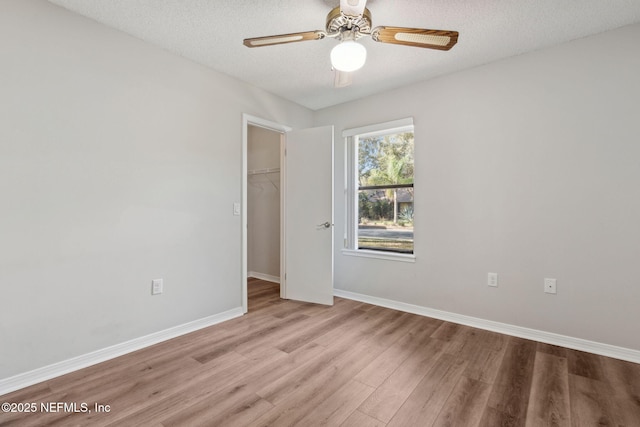 spare room featuring a textured ceiling, baseboards, and wood finished floors