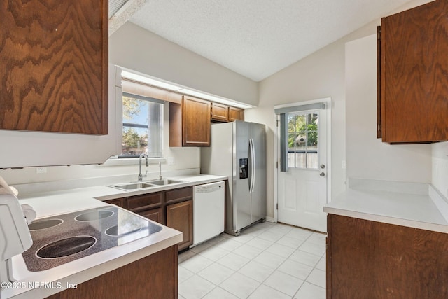 kitchen with lofted ceiling, white dishwasher, a sink, a healthy amount of sunlight, and stainless steel refrigerator with ice dispenser