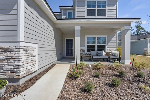 view of exterior entry with a porch and stone siding