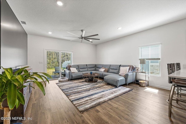 living room featuring hardwood / wood-style flooring, a textured ceiling, visible vents, and a wealth of natural light