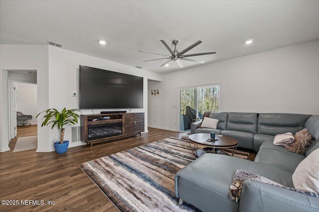 living room featuring a textured ceiling, wood finished floors, visible vents, and recessed lighting