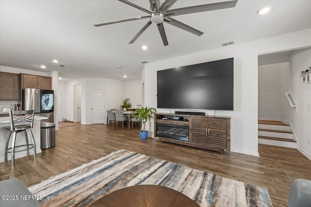 living area with a textured ceiling, dark wood finished floors, and visible vents