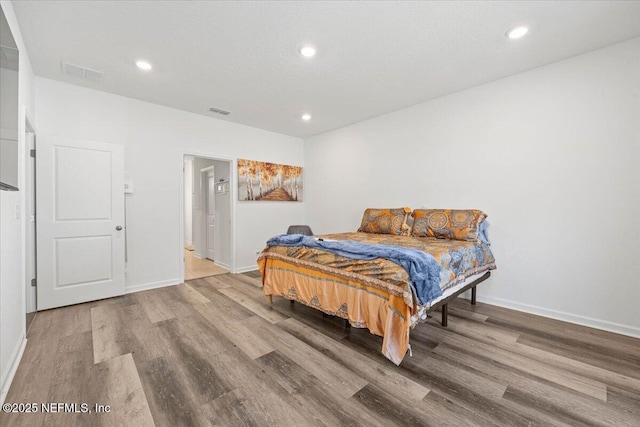 bedroom with baseboards, visible vents, wood finished floors, and recessed lighting