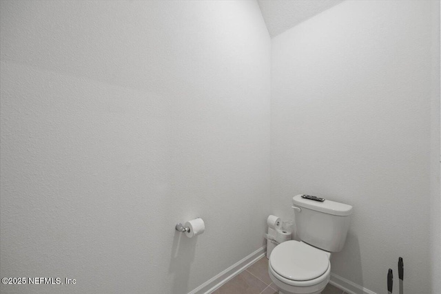 bathroom with toilet, tile patterned flooring, baseboards, and lofted ceiling