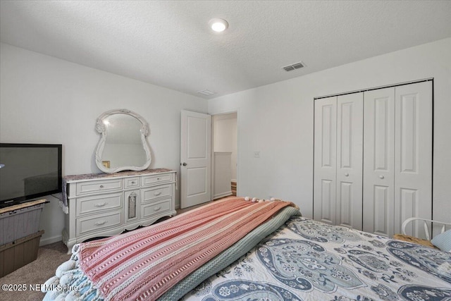 bedroom featuring a closet, visible vents, a textured ceiling, and carpet flooring