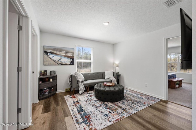 living area featuring a healthy amount of sunlight, visible vents, and wood finished floors