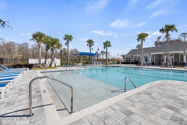 community pool with a patio area and fence