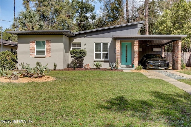 view of front of house featuring brick siding, stucco siding, fence, an attached carport, and a front lawn