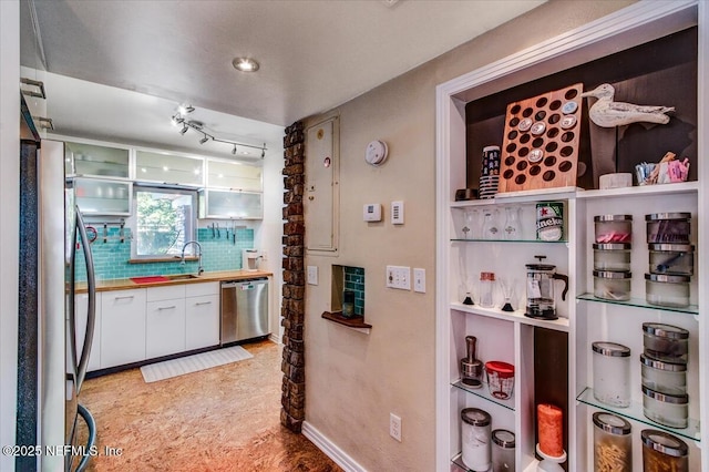 kitchen featuring stainless steel appliances, white cabinets, a sink, and tasteful backsplash