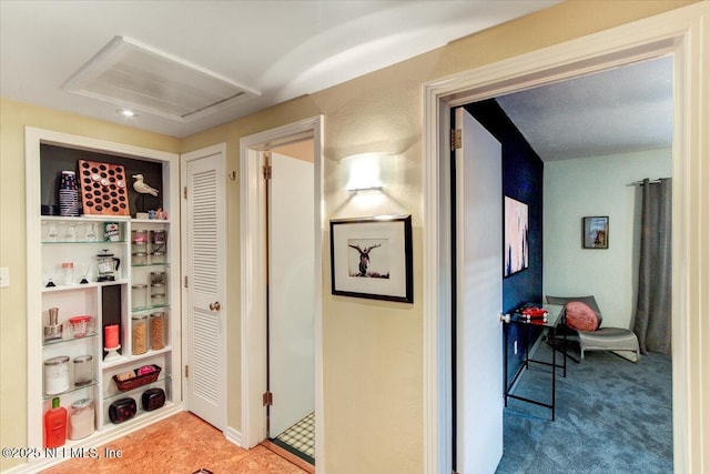 corridor with attic access and carpet flooring