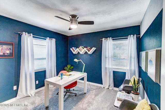 carpeted office space featuring a healthy amount of sunlight, ceiling fan, baseboards, and a textured ceiling