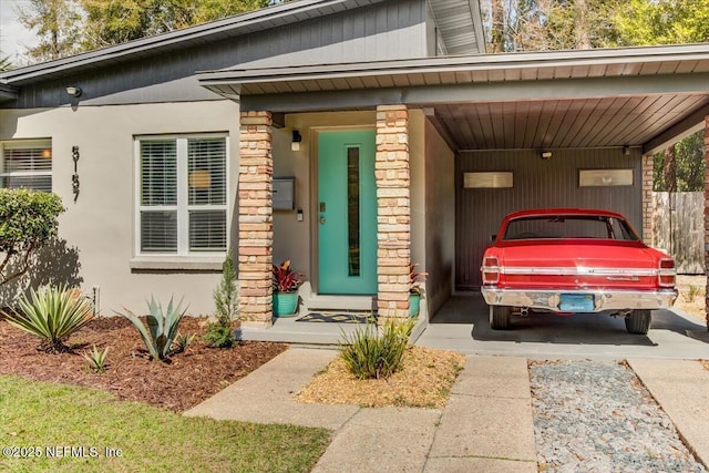 view of exterior entry featuring a carport and stucco siding