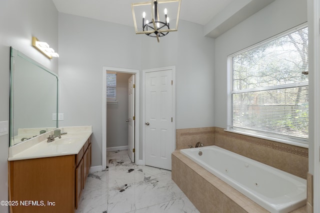 bathroom featuring a chandelier, vanity, baseboards, marble finish floor, and a tub with jets