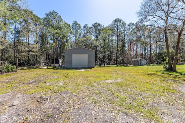 view of yard with a garage, driveway, and an outdoor structure