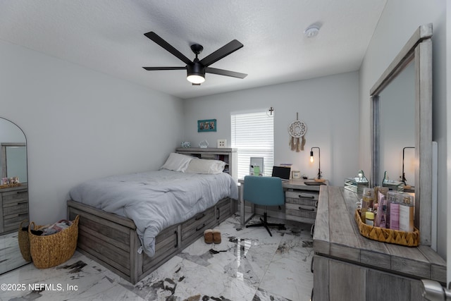 bedroom with a ceiling fan, marble finish floor, and a textured ceiling