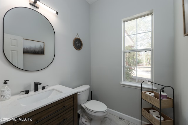 bathroom featuring toilet, marble finish floor, baseboards, and vanity