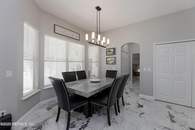 dining area with a wealth of natural light, arched walkways, marble finish floor, and baseboards