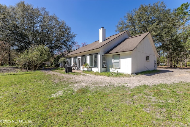 back of property with a lawn and a chimney