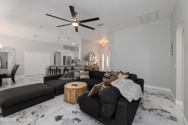 living area with arched walkways, marble finish floor, visible vents, and baseboards