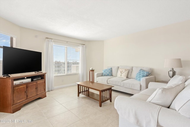 living area with light tile patterned floors, baseboards, and a textured ceiling