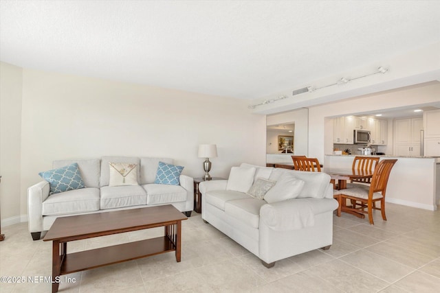 living area with visible vents, baseboards, light tile patterned floors, rail lighting, and a textured ceiling