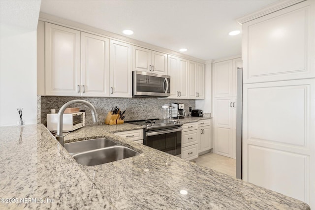 kitchen featuring decorative backsplash, light stone countertops, appliances with stainless steel finishes, and a sink