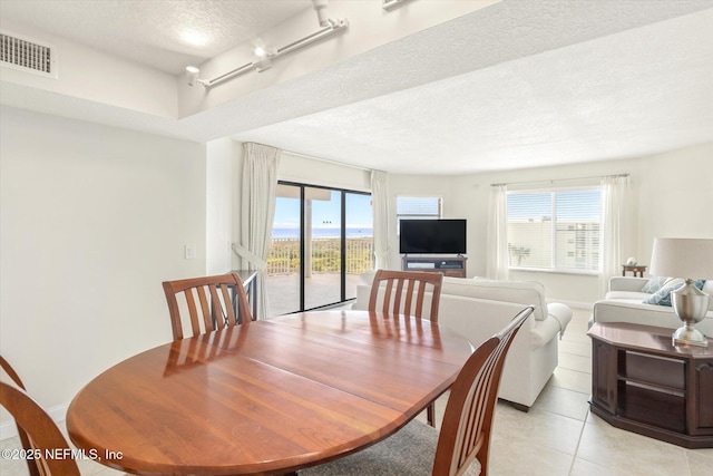 dining area with baseboards, visible vents, light tile patterned flooring, rail lighting, and a textured ceiling