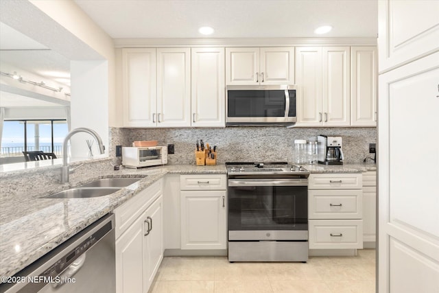 kitchen featuring backsplash, white cabinets, stainless steel appliances, and a sink