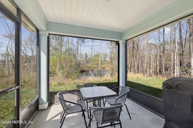 sunroom / solarium featuring wood ceiling and a wooded view