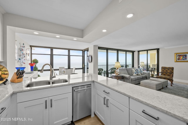 kitchen with recessed lighting, a sink, white cabinetry, light stone countertops, and dishwasher