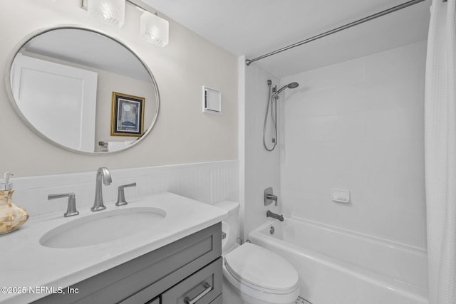 full bath with a wainscoted wall, shower / bathtub combination with curtain, toilet, and vanity