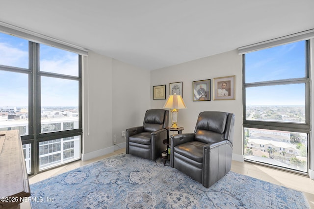 living area featuring tile patterned flooring, floor to ceiling windows, and baseboards