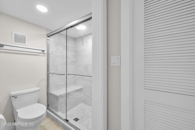 bathroom featuring toilet, a marble finish shower, visible vents, and recessed lighting