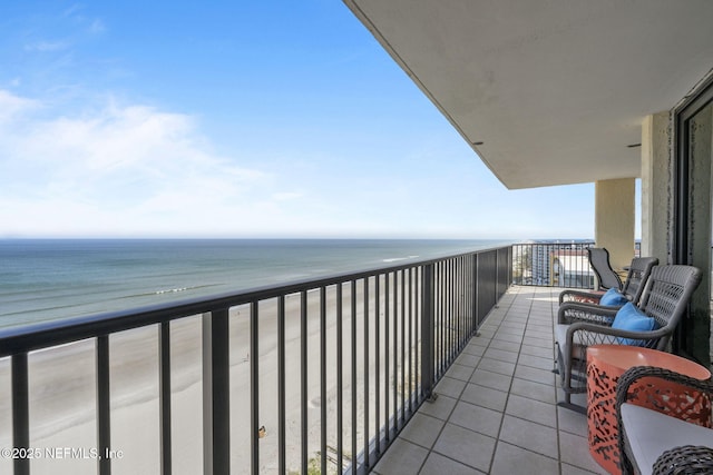 balcony with a water view and a view of the beach