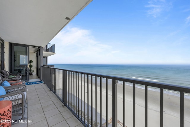 balcony with a water view and a view of the beach