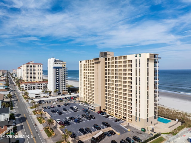 drone / aerial view with a water view, a city view, and a view of the beach