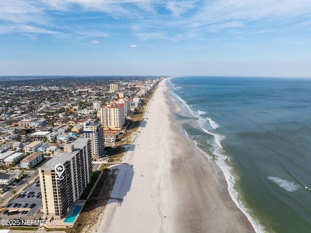 drone / aerial view with a water view, a view of the beach, and a city view