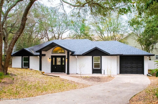 view of front facade with an attached garage, a shingled roof, and concrete driveway