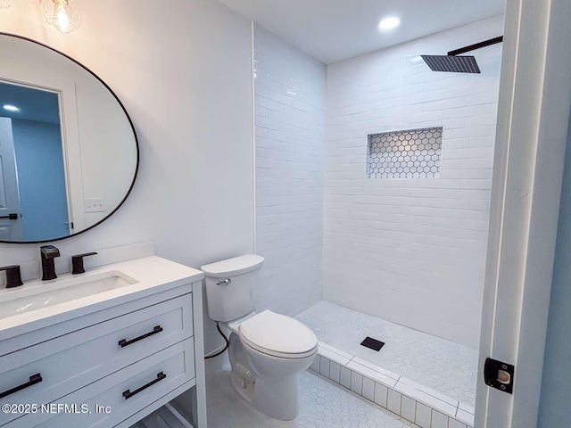 bathroom featuring a tile shower, toilet, tile patterned floors, and vanity