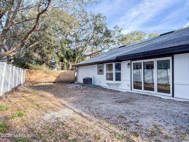 rear view of property with central AC unit and fence