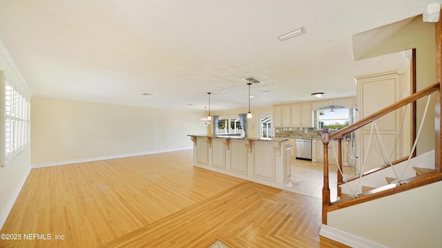 interior space with tasteful backsplash, cream cabinets, a kitchen breakfast bar, dishwasher, and baseboards