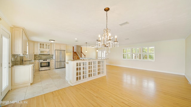 interior space with light wood-style flooring, stainless steel appliances, a sink, visible vents, and decorative backsplash