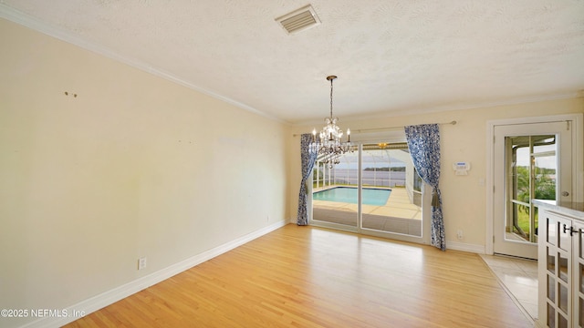 unfurnished dining area featuring a healthy amount of sunlight, light wood-style floors, visible vents, and a textured ceiling