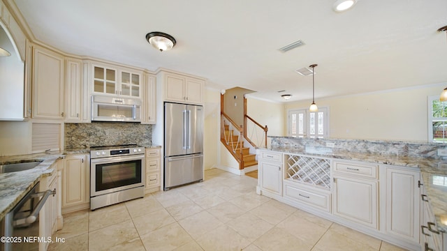 kitchen featuring visible vents, decorative backsplash, appliances with stainless steel finishes, light stone counters, and cream cabinetry