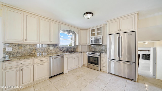 kitchen with stainless steel appliances, cream cabinets, and a sink