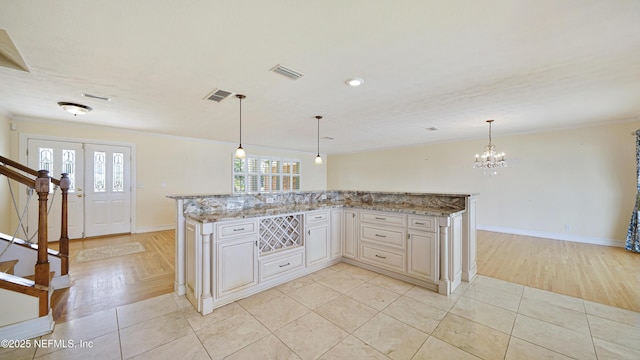 kitchen with light tile patterned floors, hanging light fixtures, visible vents, and light stone countertops