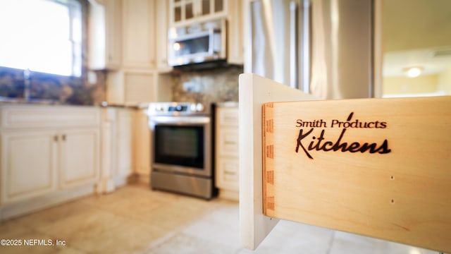 kitchen featuring light tile patterned floors, white microwave, stainless steel electric range, and white cabinets