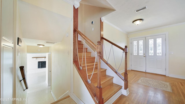 foyer with ornamental molding, visible vents, and baseboards