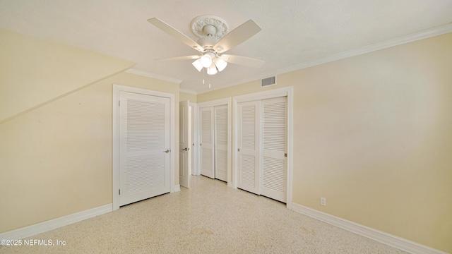 unfurnished bedroom featuring baseboards, visible vents, ceiling fan, ornamental molding, and multiple closets