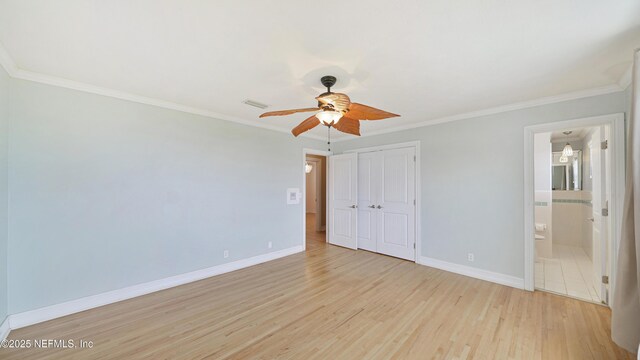 unfurnished bedroom with ornamental molding, light wood-type flooring, a closet, and baseboards